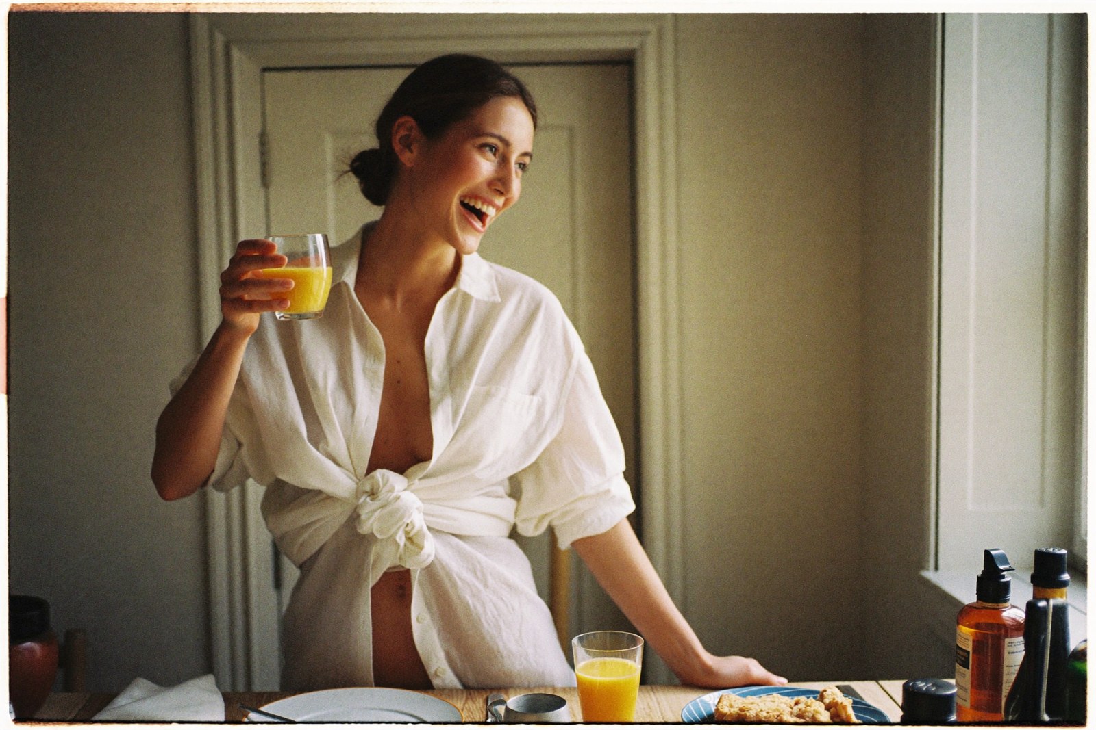 Laughing at breakfast in a white linen shirt, warm kitchen window light